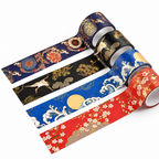Four rolls of decorative washi tape with traditional Japanese patterns in navy, black, blue, red, and brown, displayed unrolled on an open notebook.