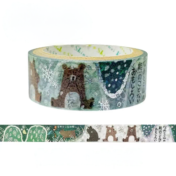 A roll of washi tape with a winter forest pattern featuring brown bears, snowflakes, and Japanese text, shown above a flat strip preview of the same pattern on a white background.