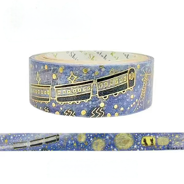 A roll of decorative washi tape featuring a blue space theme with gold stars, planets, and a train, shown alongside a flat strip of the tape on a white background.