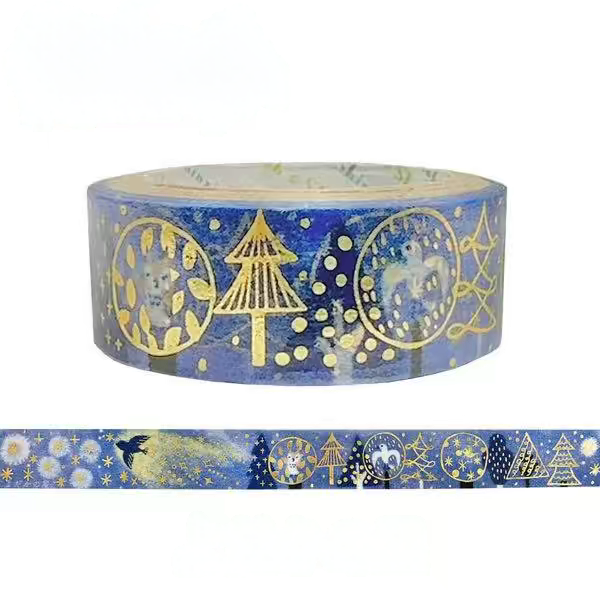 A roll of decorative washi tape with a blue background and gold foil holiday motifs, shown alongside a narrow strip of the tape displaying the printed pattern.