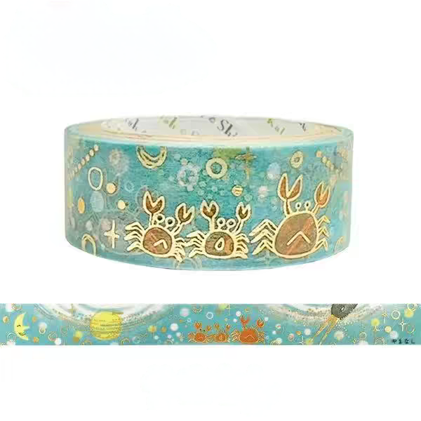 A roll of decorative washi tape with a teal blue background and gold foil crab illustrations, shown with a horizontal strip preview below on a white background.