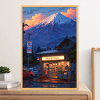 Framed artwork of a mountain and a store with 'Manion' sign, displayed on a wooden surface.
