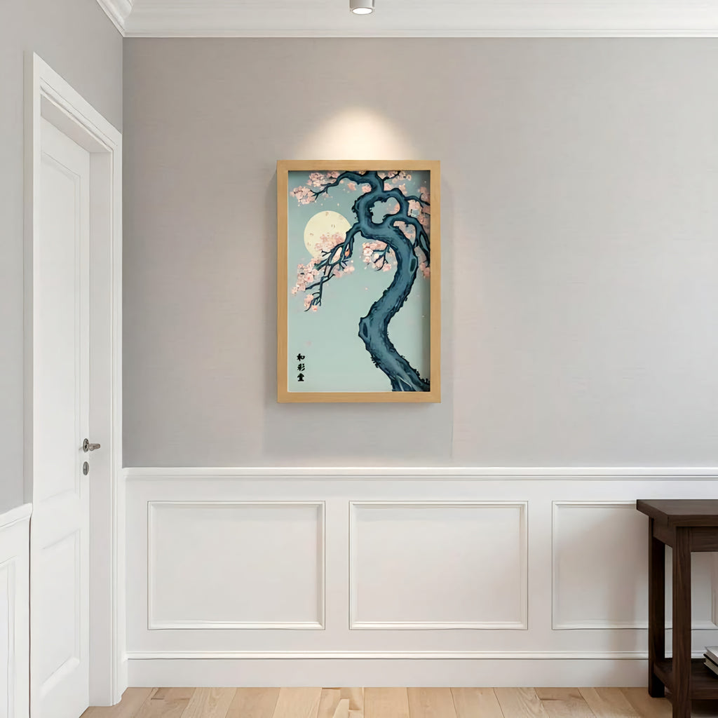 Framed artwork of a tree with cherry blossoms and a moon on a light blue background, hanging on a wall.