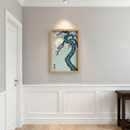 Framed artwork of a tree with cherry blossoms and a moon on a light blue background, hanging on a wall.