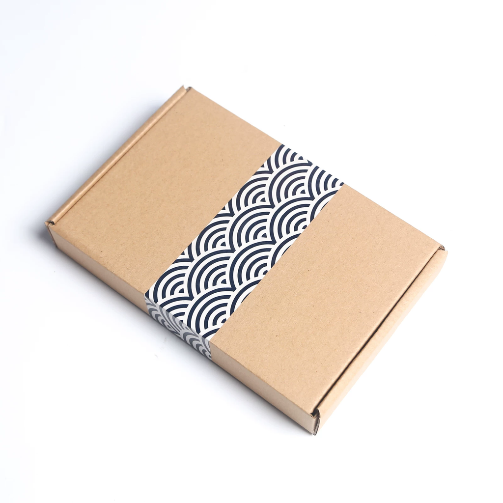 Kraft paper box with a black and white patterned tape on a white background