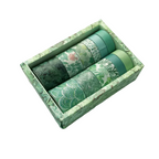 Set of green washi tape rolls in a decorative box on a white background