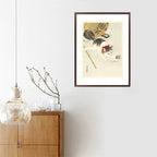 Framed artwork of a cat with a fan on a white wall above a wooden cabinet.