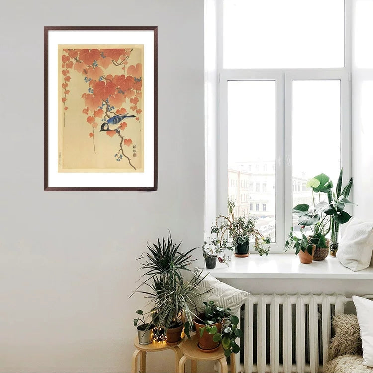 Framed artwork on a wall with plants and a window in the background