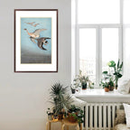 Framed artwork of birds over a beach in a room with plants and a radiator.