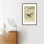 Framed artwork of an owl with cherry blossoms on a wall above a wooden cabinet.