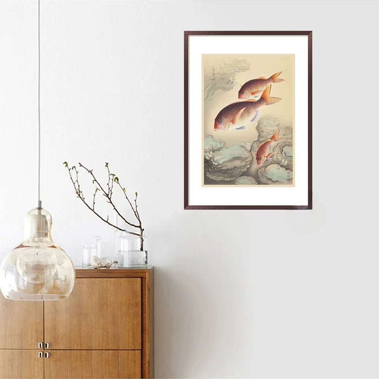 Framed artwork of fish on a wall above a wooden cabinet.