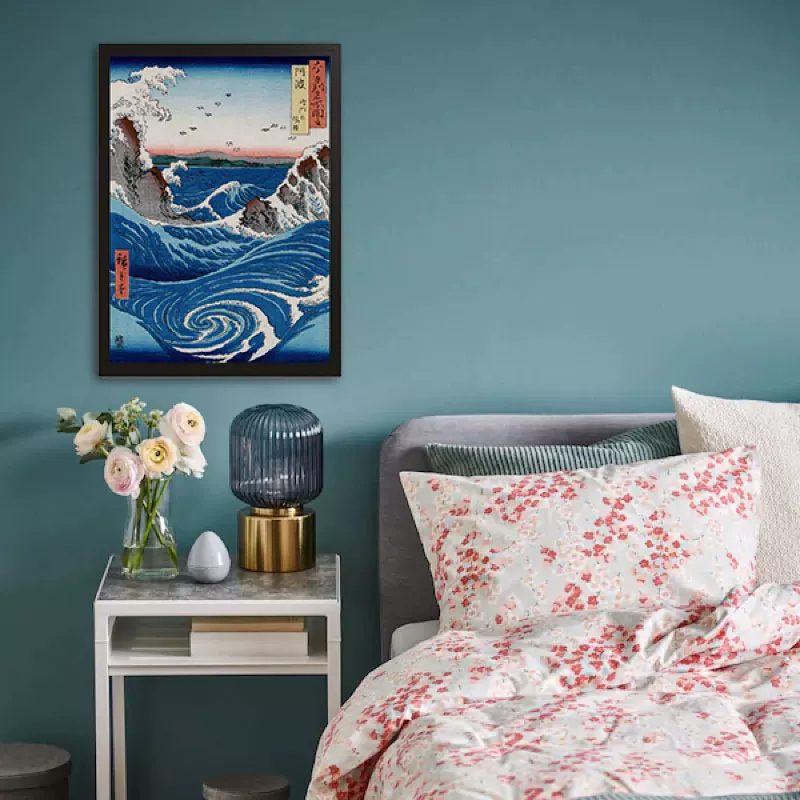 Bedroom with floral bedding, nightstand, and framed artwork on a teal wall.