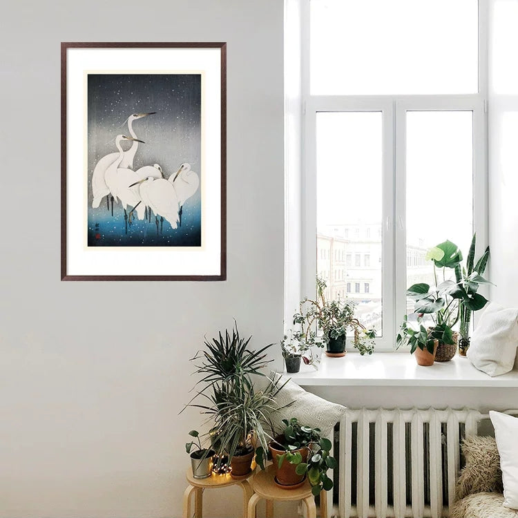Framed artwork of two dancers against a starry sky in a living room with plants and a window.