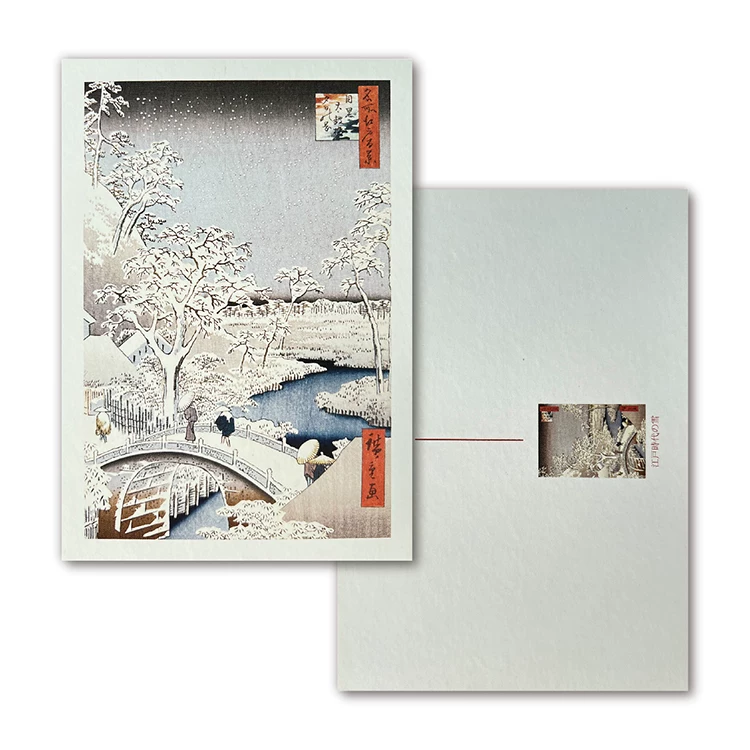 Greeting card with a snowy landscape design featuring a bridge and trees, accompanied by an envelope.
