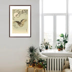 Framed artwork of an owl on a wall with plants and a window in the background