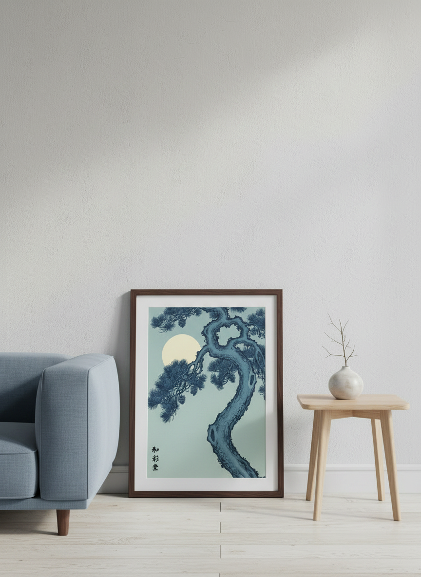 Framed artwork of a tree in a room with a gray armchair and wooden side table.